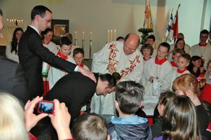 Erwachsene werden durch Dechant Andreas Weber getauft, die Paten, die Messdiener und Kommunionkinder sind Zeugen